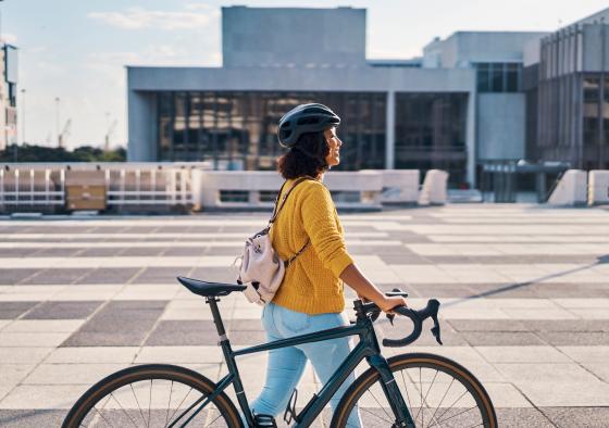 Ung kvinner går med sykkel