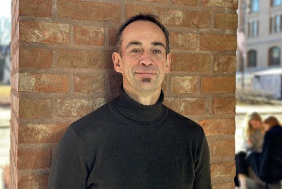 Portrett av Malcolm Langford mot en brun vegg