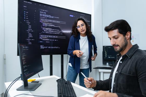 En kvinnelig og en mannlig programvareutvikler jobber med store pc-er