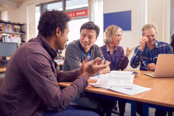 En gruppe l&aelig;rere og studenter sitter rundt et bord i et bibliotek