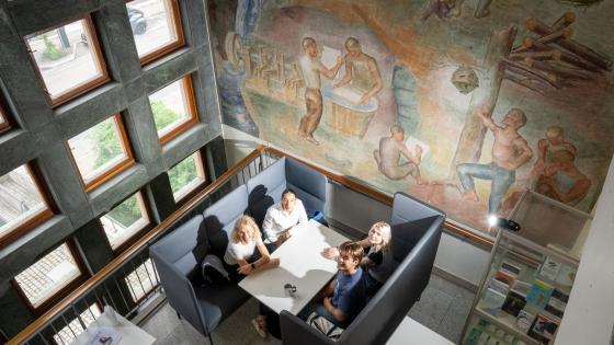 Fire studenter fra Psykologisk institutt ved UiO sitter ved et bord og jobber og ser opp på fotografen