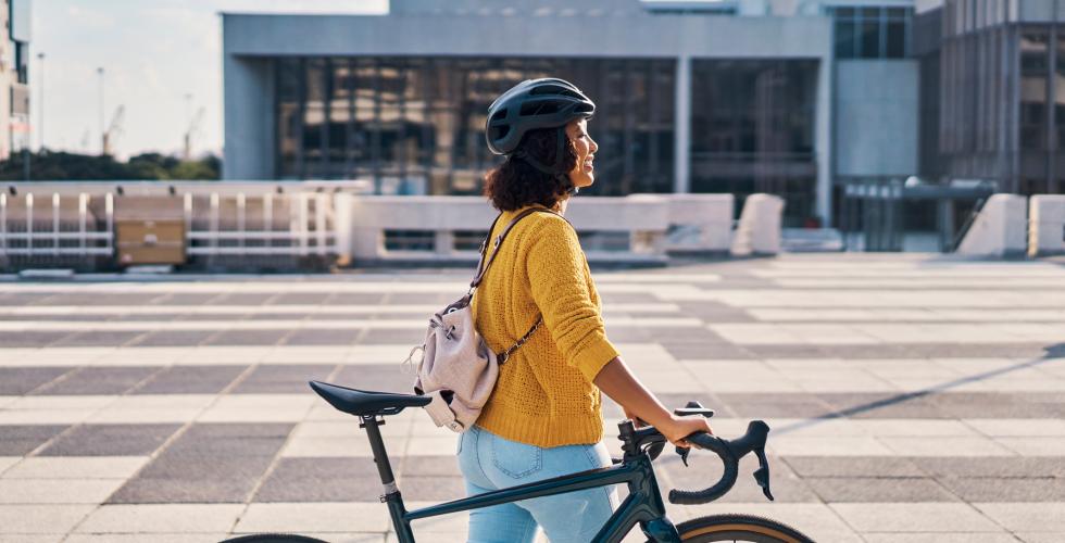 Ung kvinner går med sykkel
