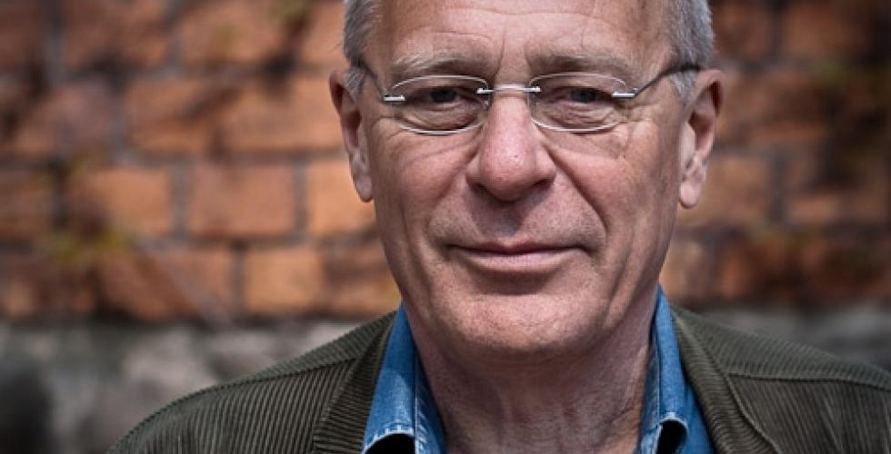 Portrettbilde av Lars Jalmert med en murvegg i bakgrunnen