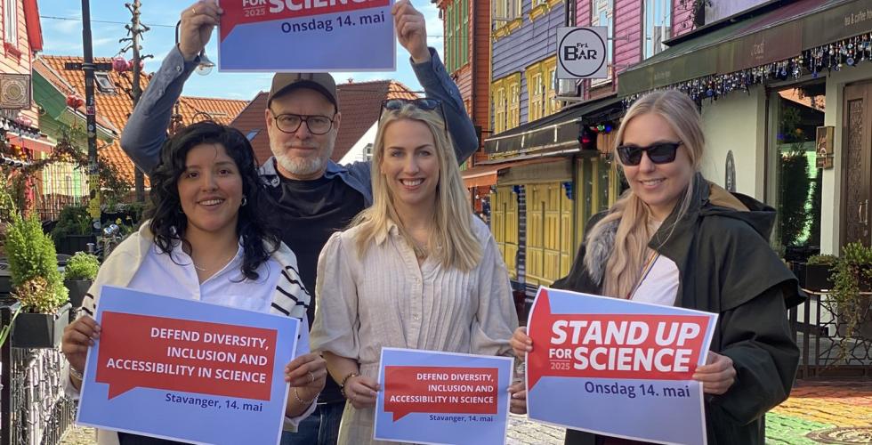 Fire smilende mennesker i Fargegata i Stavanger holder opp plakater med "Stand up for science"