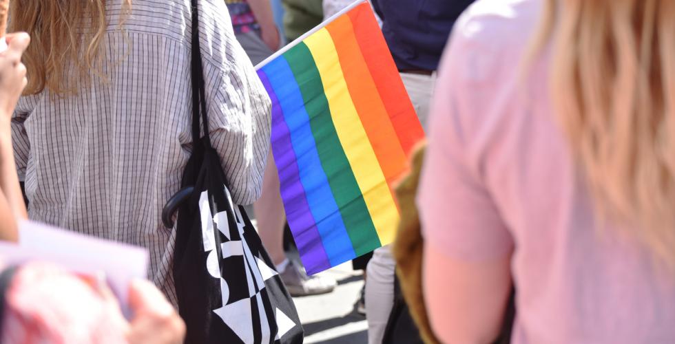 Gruppe med mennesker som markerer Pride med regnbueflagg