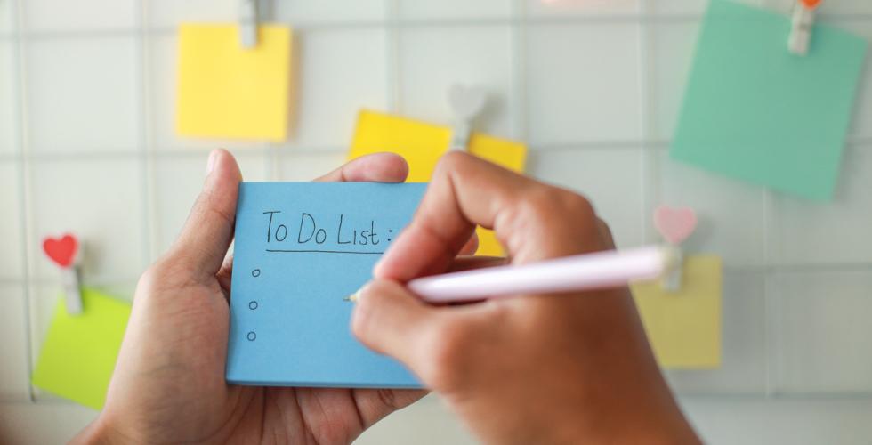 Bilde av hender som skriver to to-liste og henger opp post it-lapper